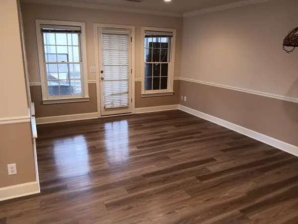 Empty room with tan walls, a white chair rail and dark wood-look flooring, french doors to the rear