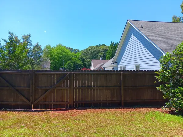 Dark-stained wood privacy fence along a back lawn, painted gable end behind