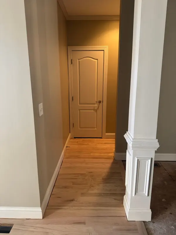 Hallway in warm tan with white column casing and trim over light hardwood