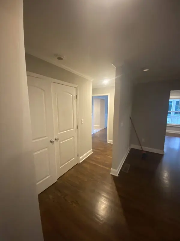 Interior hallway with white walls and doors over dark stained hardwood