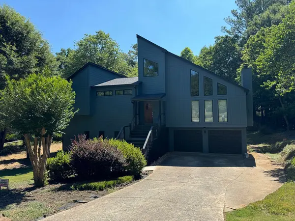 Contemporary multi-gable home painted slate blue-gray with tall window walls
