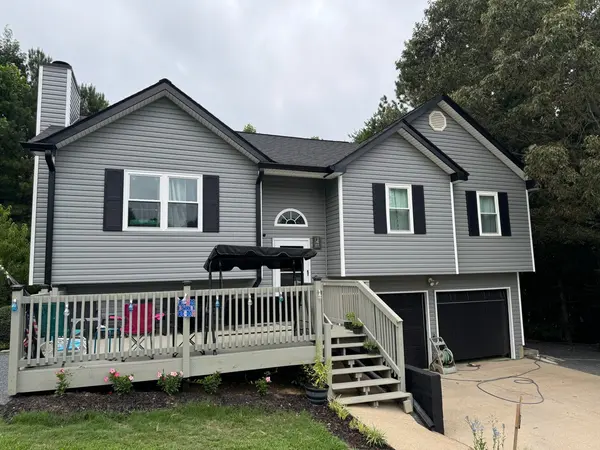 Gray split-level home with black shutters and a white-railed front deck