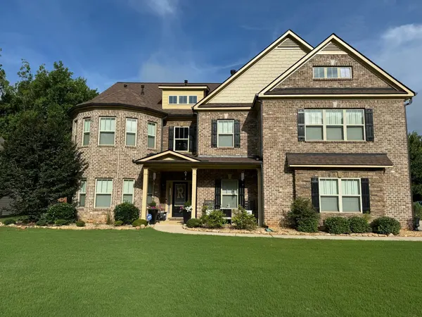 Large two-story home in brick and tan siding with a covered front porch