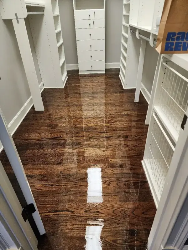 Walk-in closet with white shelving over freshly refinished hardwood