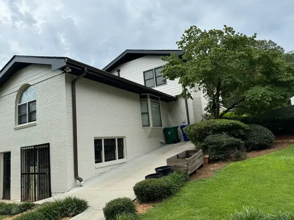 White painted brick home with dark trim and a concrete walkway