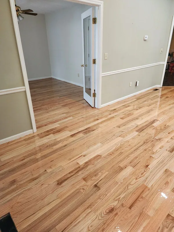 Light oak floor running through a doorway into the next room, cream walls and chair rail