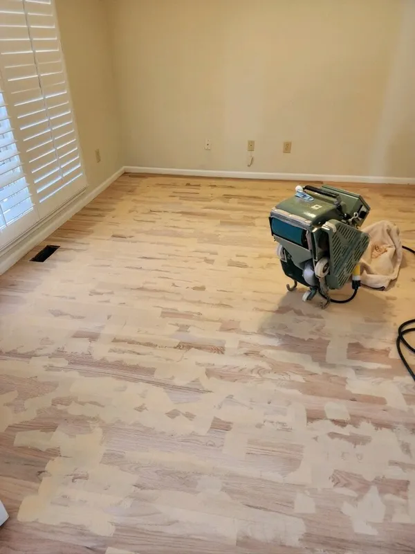 Red oak strip floor part way through sanding, drum sander standing in an empty room