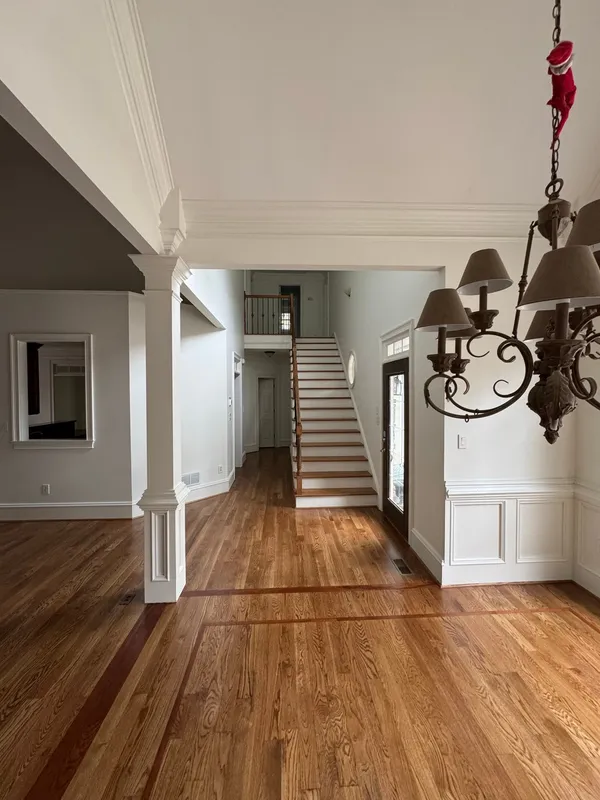 Two-story entry with hardwood, white columns and a painted stair beyond