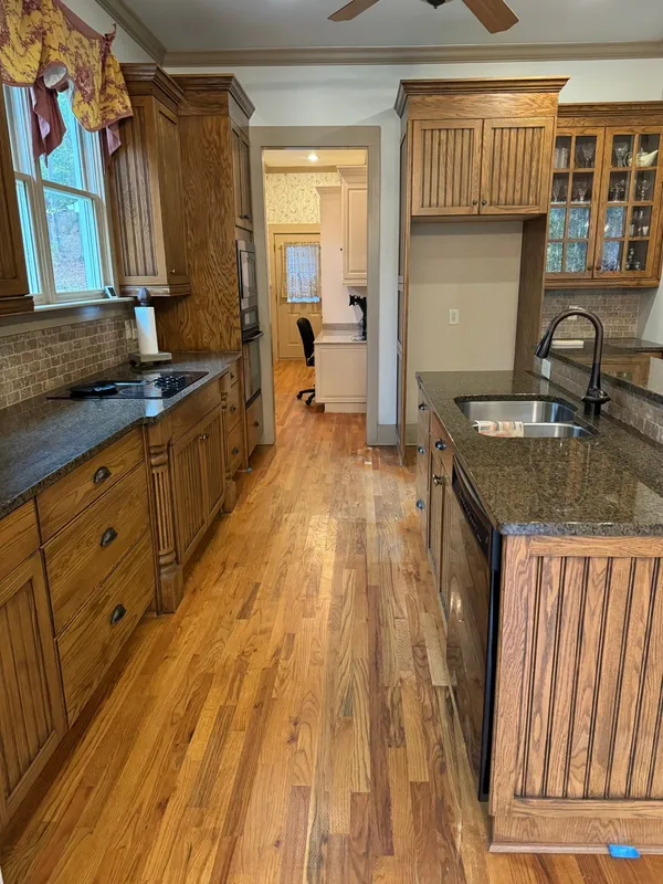 Kitchen with stained timber cabinets, granite tops and an undermount sink, oak floor running through