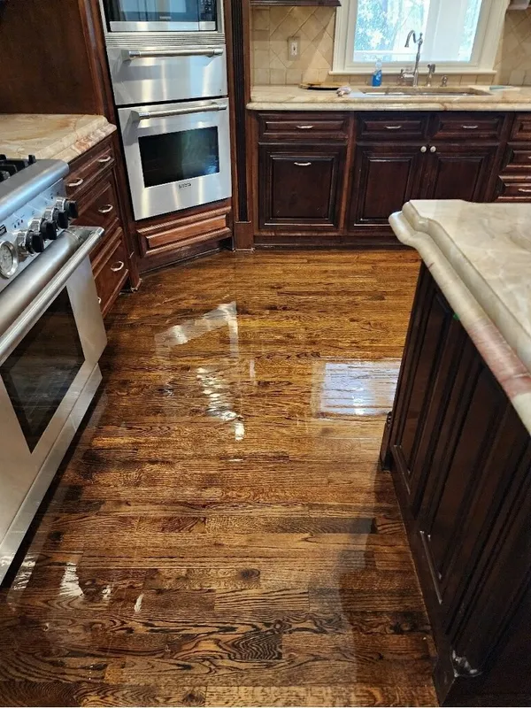 Dark stained cabinets with a wall oven and gas range, hardwood refinished and still wet
