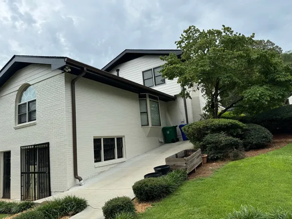 White painted brick elevation with dark trim and a side path
