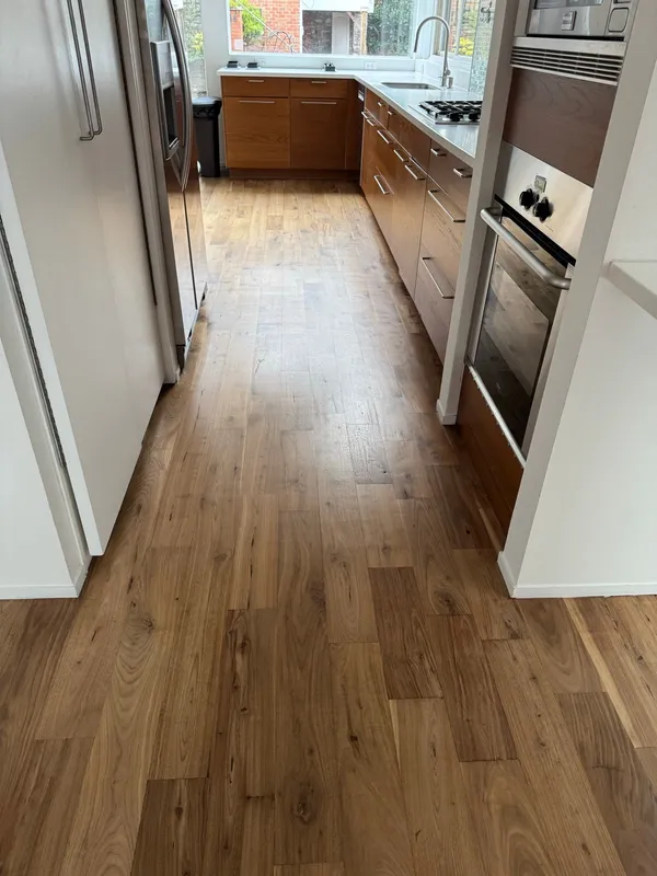 Galley run of timber cabinets with a built-in wall oven over a timber floor