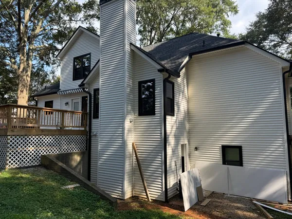 White siding and chimney chase with a deck and lattice skirt below