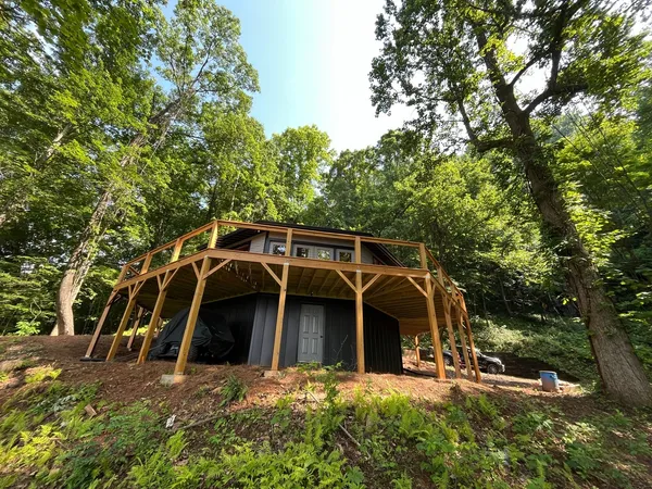 Timber pavilion framing built over an outbuilding on a slope