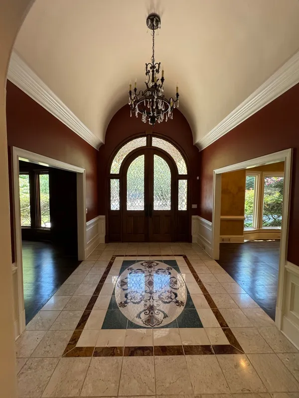 Tiled entry with a stone mosaic medallion, arched timber doors and deep red walls