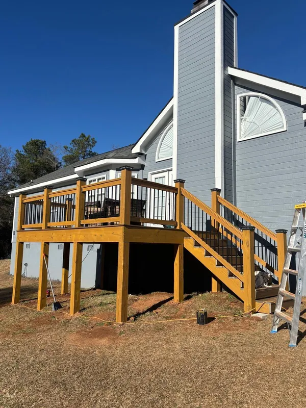 Deck and stair with black balusters against gray shingle siding, ladder still up