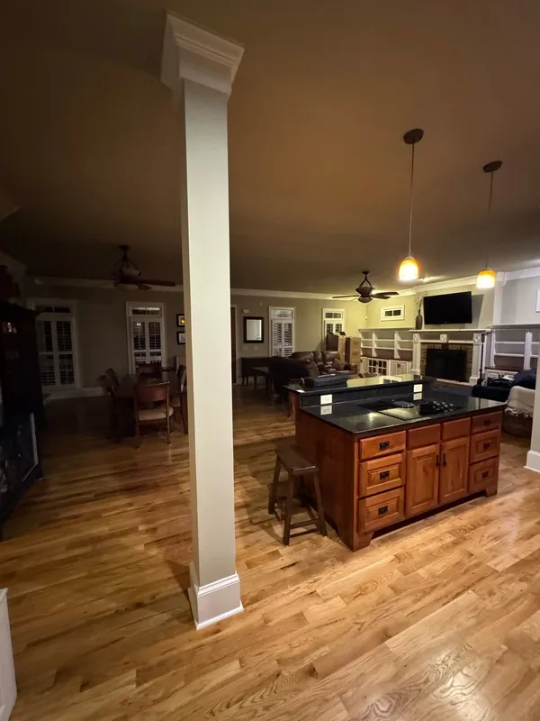 Timber island with a cooktop seen through a cased opening into the living area