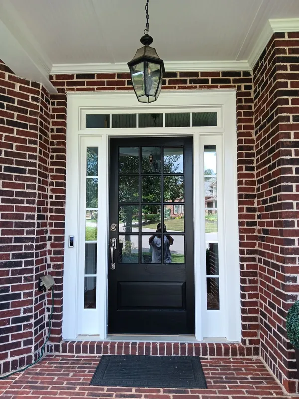 Black glazed front door with sidelights set into red brick with white trim