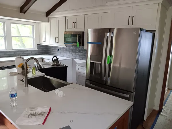 White shaker kitchen with a gray subway backsplash, marble-look quartz tops and a stainless French-door fridge
