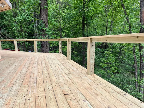 Treated deck boards and timber rail finished out against the tree line