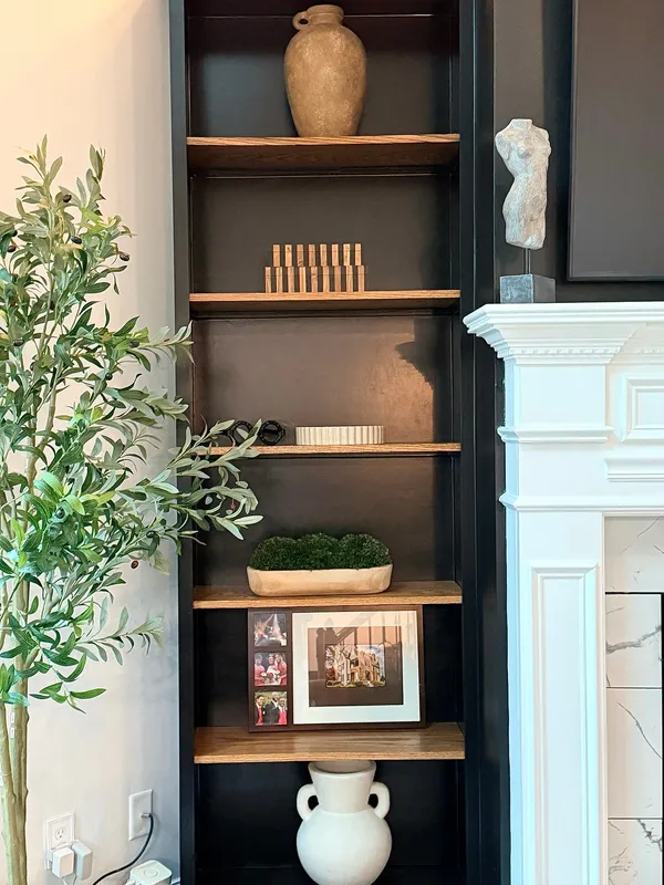 Dark painted built-in shelving beside a white painted fireplace surround
