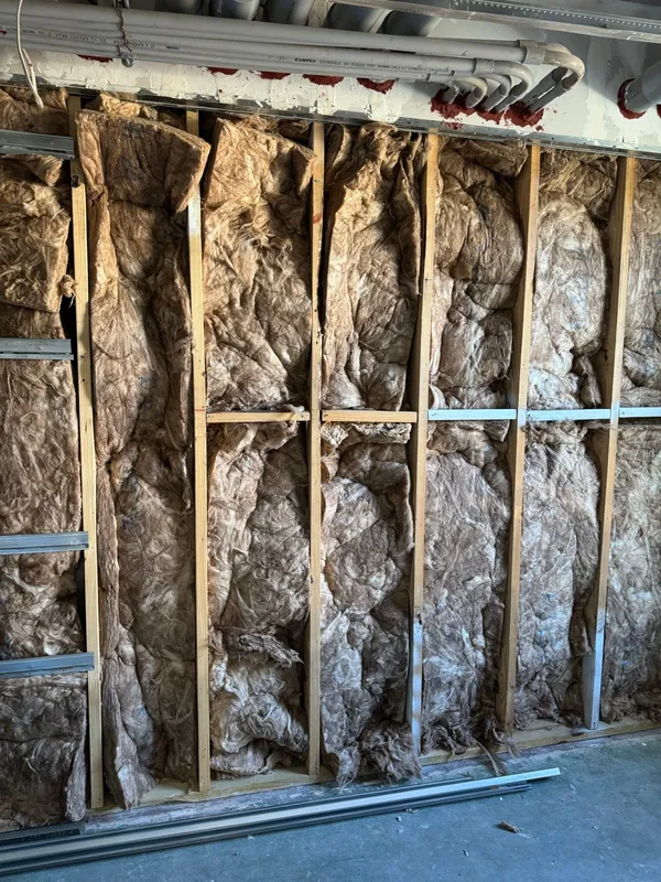 Stud bay opened up with fiberglass insulation exposed before new board goes on