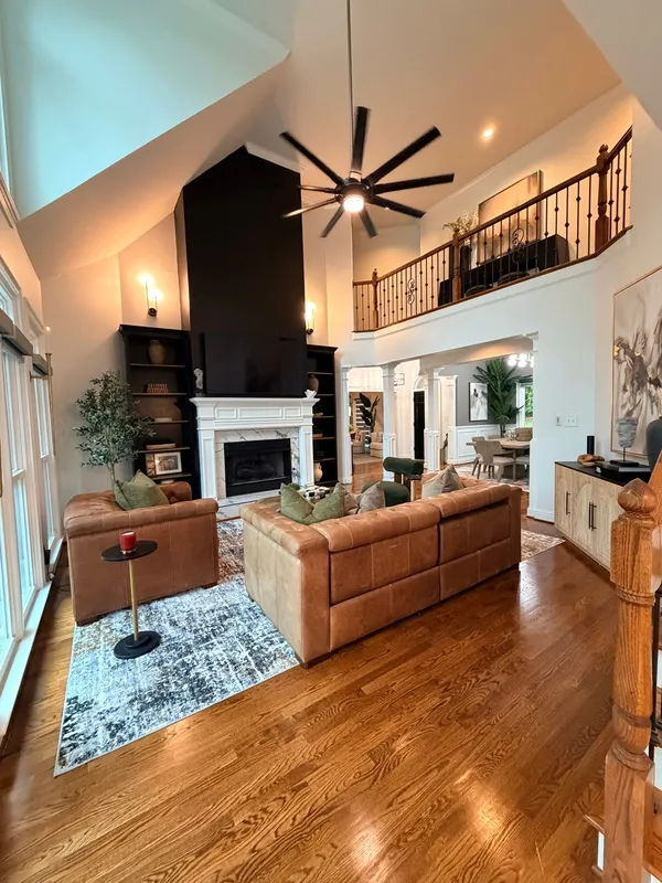 Two-story living room with a fireplace, timber balcony rail and hardwood floor