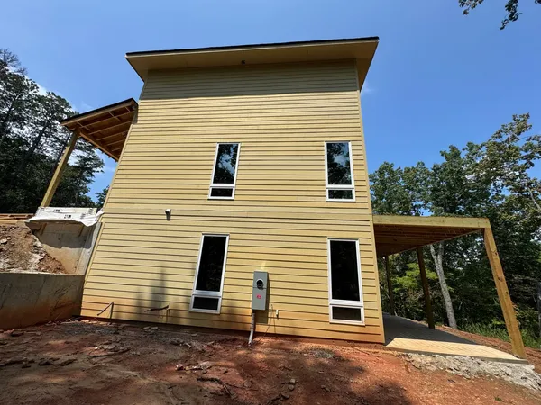 Fresh yellow-tan lap siding on a new build with a carport framed alongside
