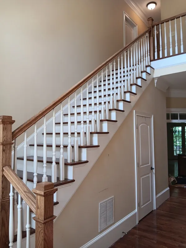 Painted stair with white balusters and a stained timber handrail