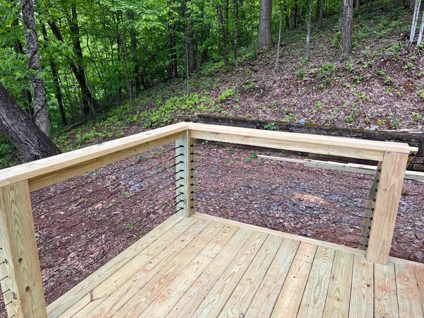 New treated deck with cable railing cut into a wooded hillside